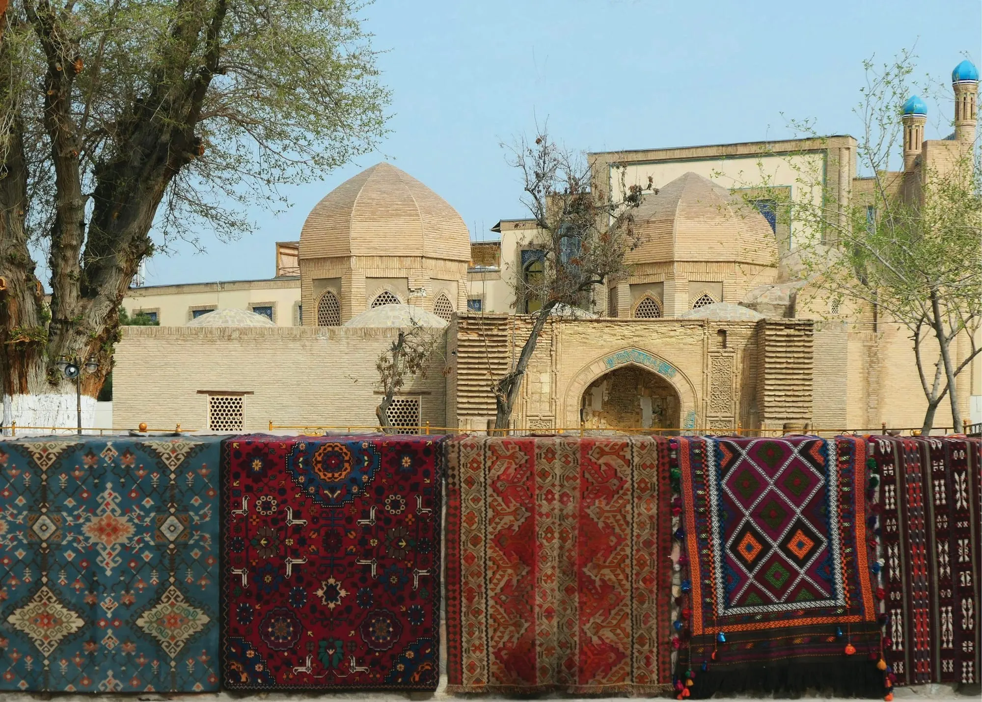 Tapijten hangen te koop voor een oude madrassa in Bukhara